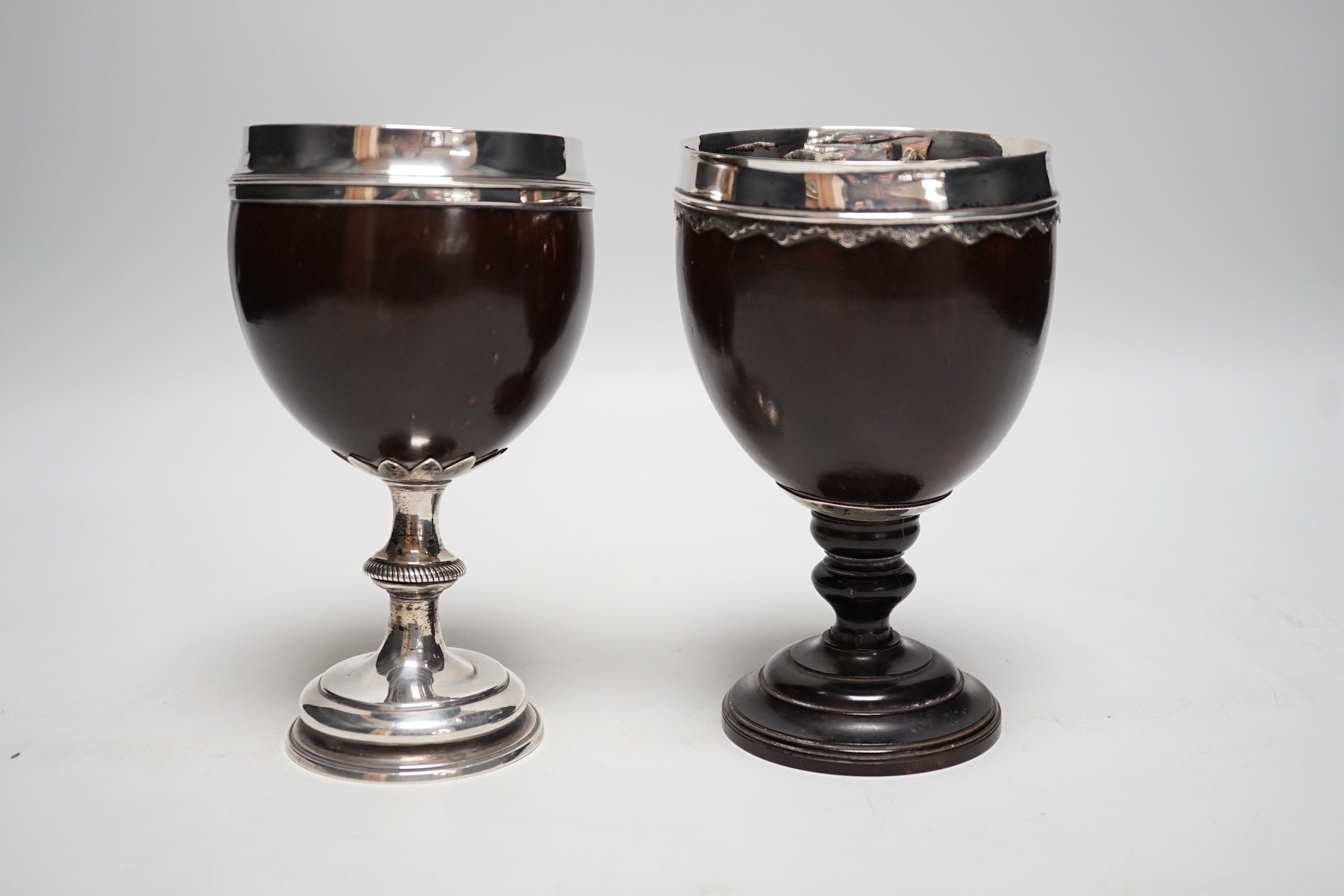 Two late 18th century white metal mounted pedestal coconut cups, one hallmarked silver for John Robbins?, London, 1764, 14.4cm, the other with white metal mounted top rim, on turned wooden base.
